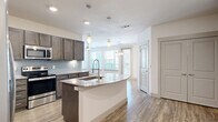 This well-appointed 3-bedroom, 3-bathroom residence in Allen, Texas offers a thoughtfully designed single-floor layout that balances comfort and functionality. The open-concept living area seamlessly connects the kitchen, dining, and living spaces, creating an inviting and versatile environment filled with natural light from multiple windows.

The kitchen is a standout feature, showcasing rich dark cabinetry, a light gray subway tile backsplash, stainless steel appliances, and a curved granite-topped island with an integrated sink and stylish pendant lighting overhead. Wood-style plank flooring extends throughout the main living areas, lending warmth and continuity to the space.

Each of the three bedrooms offers plush carpet flooring and natural light, with several rooms featuring direct access to their own dedicated closets. The primary bedroom includes a generously sized walk-in closet and an en-suite bathroom appointed with a dual-sink granite vanity, dark cabinetry, wood-look tile flooring, and a tiled shower-tub combination.

Additional highlights include six closets distributed throughout the unit for abundant storage, a dedicated laundry area, and a clean, neutral color palette that provides a bright and modern aesthetic. The layout is practical and efficient, making excellent use of every square foot available.