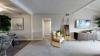 Located in Cypress, CA, this well-appointed two-bedroom, two-bathroom residence offers a thoughtfully designed single-floor layout. The inviting living room is a standout feature, boasting vaulted ceilings with exposed white beams and a sliding glass door that opens to a private balcony, filling the space with natural light and outdoor views. Soft carpet underfoot and neutral gray walls create a warm, cohesive ambiance throughout.

The dining area, positioned adjacent to the kitchen, features wood-look flooring and a ceiling fan, providing a functional yet stylish space for everyday meals. The galley-style kitchen is outfitted with rich dark cabinetry, granite-look countertops, stainless steel appliances including a gas range and refrigerator, and a double sink — maximizing efficiency in a compact footprint.

The spacious primary bedroom offers plush carpeting, a large window with outdoor views, and a textured ceiling, while the second bedroom is versatile and well-lit with ample room. Both bathrooms are finished with dark wood vanities, granite-look countertops, chrome fixtures, and wood-look flooring. A dedicated closet and hallway complete this efficiently organized home.