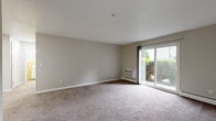 Located at 55 Sharon Rd in Waterbury, CT, this one-bedroom, one-bathroom unit offers a practical and comfortable single-floor layout. The living room is generously sized, featuring soft wall-to-wall carpeting, neutral gray-toned walls, and a sliding glass door that fills the space with natural light and provides views of the surrounding greenery. A wall-mounted air conditioning unit and baseboard heating ensure year-round comfort.

The galley-style kitchen is well-appointed with crisp white shaker cabinetry, light marble-look countertops, wood-look flooring, and a full suite of black appliances including a refrigerator, range, microwave, and dishwasher. A stainless steel sink adds a modern touch to this efficient and functional cooking space.

The bedroom is a comfortable size, offering plush carpeting, neutral walls, a built-in closet, and baseboard heating. A connecting hallway provides a smooth transition between rooms.

The bathroom features distinctive yellow ceramic tile wainscoting, wood-look flooring, a white vanity with a clean countertop, a large mirror, and a full-size tub and shower combo with a curtain rod. The overall ambiance of the unit is clean, neutral, and move-in ready.