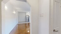 Located at 1660 Bathurst Street in Toronto's Forest Hill neighbourhood, this one-bedroom, one-bathroom unit offers a practical and well-laid-out single-floor plan. Warm hardwood flooring flows throughout the living areas and bedroom, lending a classic character to the space. The open connection between the living room and hallway entry — marked by a charming arched doorway — creates an easy sense of flow, with crown moulding adding a refined architectural touch. The living room is bright and airy, featuring natural light and a clean, neutral palette. The galley-style kitchen is efficiently designed with white cabinetry accented by brushed gold hardware, gleaming tile flooring, a stainless steel refrigerator, and modern appliances including a stainless steel range. A window above the sink allows for natural light. The bedroom is a comfortable size, featuring hardwood floors, a classic cast-iron radiator, and a window overlooking the surrounding neighbourhood. Two closet doors provide ample storage. The bathroom is finished with large-format grey tile surrounding a full soaker tub with overhead shower, complemented by a frosted window for privacy and natural light.