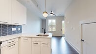 Located at 222 West Blvd in Charlotte's vibrant 28203 neighborhood, this modern two-story residence showcases sleek contemporary design throughout. Rich dark hardwood-style flooring flows consistently across both levels, complemented by crisp white walls and clean architectural lines that create a bright, cohesive aesthetic.

The open-concept kitchen serves as a centerpiece of the main level, featuring white flat-panel cabinetry with matte black hardware, striking quartz countertops, and a bold navy chevron-patterned tile backsplash. Stainless steel appliances — including a range, microwave, and refrigerator — complete the space, while a kitchen island with an undermount sink and matte black faucet offers additional workspace and casual dining potential. A globe pendant light and ceiling fan add stylish, functional touches to the adjoining living area, which benefits from natural light through large windows and direct outdoor access.

A half bath on the main floor provides a clean, minimalist powder room with a white floating vanity and matte black accents. Upstairs, a spacious primary bathroom impresses with a wide double-sink vanity, dual black-framed mirrors, and designer sconce lighting. Generously proportioned rooms throughout offer flexible living arrangements, and the multi-level layout — visible in the 3D dollhouse view — provides a well-defined sense of separation between living and private spaces.