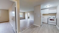 Located in Hartford, CT, this single-floor residence offers a clean, functional layout with a cohesive neutral color palette throughout. Light-toned hardwood-style flooring runs continuously across the living spaces, lending a sense of openness and easy flow between rooms.

The open living and dining area is bright and airy, benefiting from multiple windows that allow natural light to pour in. Baseboard heating units are present throughout, ensuring comfort during New England winters. The living spaces are generously proportioned, with views of mature trees visible through large windows, adding a refreshing natural element to the interior.

The kitchen is thoughtfully laid out with white cabinetry, white appliances including a refrigerator and an electric range, and light countertops. A partial wall divides the kitchen from the main living area, maintaining an open feel while defining each functional zone.

The bedroom features a large double-pane window framing a lush, tree-lined view, with a baseboard heater positioned beneath it. The room is well-lit and offers ample wall space.

The bathroom is finished with tile flooring, a tub and shower combination with marble-style tile surround, a white vanity with under-cabinet storage, a mirrored medicine cabinet, and standard fixtures — providing a clean, practical space.