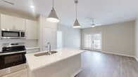 Located at 1090 Summersweet Drive in New Bern, NC, this thoughtfully designed 3-bedroom, 2-bathroom home offers comfortable single-floor living with contemporary finishes throughout. Light wood-look flooring flows seamlessly across the space, complementing the neutral, warm-toned walls found in every room.

The kitchen is a standout feature, outfitted with white shaker-style cabinetry, stainless steel appliances, a subway tile backsplash, and a peninsula with an undermount sink — ideal for both cooking and casual dining. The adjacent living room benefits from natural light and French doors that open to the outdoors, with a ceiling fan adding to the airy feel.

Each of the three bedrooms is well-proportioned, featuring windows with blinds, ceiling fans, and generous natural light. The spacious primary bedroom connects to an en-suite bathroom with a dual-sink vanity, quartz countertops, and ample cabinetry. A walk-in closet with wire shelving and hanging rods provides excellent storage. The second bathroom mirrors the same clean, modern aesthetic with a single-sink vanity and wood-look flooring.

A dedicated laundry room houses a full-size washer and dryer with overhead wire shelving. The hallway provides seamless connectivity throughout the home, completing this well-appointed and move-in-ready residence.