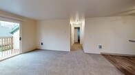 Located in Gresham, Oregon, this single-floor 2-bedroom, 2-bathroom home offers a functional and comfortable layout. The open-concept kitchen and living area serves as the heart of the home, with the kitchen featuring light wood cabinetry, stainless steel appliances including a full-size refrigerator and electric range, wood-look flooring, a peninsula with countertop seating, and a ceiling fan overhead. The living room flows naturally from the kitchen and is finished with plush carpeting, leading to a sliding glass door that opens to a private deck with outdoor views.

A hallway connects the two carpeted bedrooms, each offering natural light from windows. The primary bedroom features mirrored sliding closet doors, while both bedrooms include dedicated closet space. Two full bathrooms serve the unit, each equipped with a tub/shower combination, vanity with granite-style countertops, light wood cabinetry, and wood-look flooring. The overall ambiance is clean and neutral, with warm beige tones throughout, creating a move-in ready environment well-suited for comfortable everyday living.