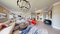 Located at 635 Bay Ave in Toms River, NJ, this single-floor clubhouse showcases a thoughtfully curated coastal-contemporary aesthetic throughout its open, flowing layout. The main lounge area serves as the centerpiece of the space, anchored by a striking circular chandelier with cascading pendant lights that draws the eye upward. Generous windows invite abundant natural light and offer views of the surrounding community, creating a bright and welcoming atmosphere. The seating area features a large neutral sectional sofa complemented by bold coral-red accent chairs, all arranged atop a vivid blue-and-taupe abstract area rug that reinforces the coastal theme. Large-scale artwork adorns the walls, adding a curated, polished character to the space.

Adjacent to the lounge is a versatile bar and kitchenette area, outfitted with white shaker cabinetry, granite countertops, and a matte black faucet at the undermount sink. A row of bar-height seating lines the window-facing counter, offering additional workspace or casual gathering space alongside wall-mounted televisions. Shiplap wall accents throughout lend a clean, nautical touch, tying the interior design together cohesively. The overall ambiance is refined yet relaxed, reflecting a modern coastal sensibility suited to community gathering and leisure.