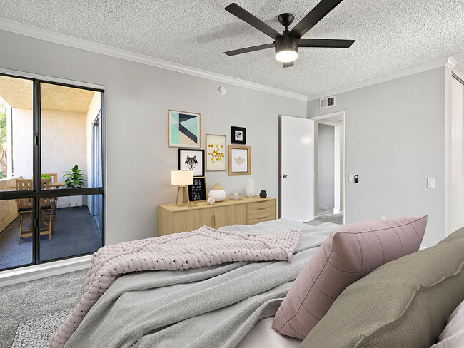 Carpeted bedroom with ceiling fan and natural light from adjacent patio. - Chandler Circle