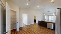 This single-story home showcases a thoughtfully designed open-concept layout, where the living area flows seamlessly into the kitchen. The living space is anchored by soaring vaulted ceilings with a ceiling fan, rich dark hardwood-style flooring, and large windows fitted with blinds that allow generous natural light to fill the room. The kitchen is well-appointed with dark espresso cabinetry, granite-style countertops, a peninsula with a sink, pendant lighting, and a full suite of stainless steel appliances including a refrigerator, electric range, and built-in microwave. A walk-in closet with wire shelving provides ample storage off the main living area. The bedrooms feature neutral carpet, ceiling fans, and windows that bring in natural light. Two bathrooms serve the home: one with a tub-shower combination, hardwood-style flooring, and dark vanity cabinetry, and another with a standalone shower stall, granite-topped vanity, and coordinating finishes. The attached garage is spacious, finished with a smooth concrete floor, recessed lighting, and an automatic garage door opener, completing this well-equipped home.