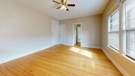 This single-floor unit offers a thoughtfully laid-out interior that blends classic architectural character with modern updates. The kitchen serves as a standout feature, showcasing rich dark wood cabinetry, light granite-style countertops, and a full suite of stainless steel appliances including a gas range, dishwasher, and refrigerator. A wall-mounted range hood, undermount sink, and a peninsula provide both functionality and style. Light-toned vinyl flooring in the kitchen transitions seamlessly to warm hardwood floors in the adjacent living and entry areas, where natural light pours in through windows and a classic white paneled entry door adds to the space's charm. Cast iron radiators throughout speak to the building's historic character. The bedrooms are carpeted for comfort and each features a ceiling fan with light fixture, generous closet space, and windows that invite natural light. One bedroom includes a walk-in style closet, while the other offers a standard reach-in closet alongside a direct view into the kitchen area. The overall palette of neutral walls, white trim, and warm flooring tones creates a cohesive, inviting ambiance throughout the unit.