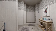 Located at 3964 Watercourse Dr in Fort Worth, TX, this purpose-built dog wash facility offers a well-designed, single-room space thoughtfully appointed for pet grooming. The interior is finished with large-format light gray wall tiles on the lower half and striking silver and white mosaic pebble tiles wrapping the upper walls and ceiling, lending the space a clean yet visually dynamic aesthetic.

The room features two walk-in shower stalls with mosaic-tiled floors and linear drains, each equipped with a handheld showerhead and grab bar for ease of use during pet bathing. Soft area rugs placed at the stall entrances add a practical touch. A wall-mounted utility sink with overhead cabinetry and a grooming station with a built-in dryer provide a fully equipped area for post-bath finishing. A rustic wood console table along one wall offers convenient storage for grooming supplies, complemented by a wire basket for additional organization.

The flooring throughout the main area consists of wood-look porcelain tiles, providing durability and easy maintenance. A wall-mounted mini-split HVAC unit ensures year-round climate control. Charming pet-themed artwork adorns the walls, contributing to the welcoming ambiance of this efficient and attractively designed dog wash space.