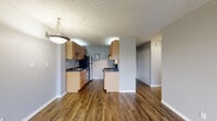 Located at 10306 Meridian Avenue North in Seattle, WA, this one-bedroom, one-bathroom unit offers a well-organized floor plan that makes efficient use of its space. The open-concept living, dining, and kitchen area serves as the heart of the unit, featuring rich hardwood-style flooring that flows throughout the main living spaces. A large sliding glass door fills the living room with natural light and opens directly onto a private balcony, offering pleasant views of the surrounding neighborhood and green spaces.

The kitchen is thoughtfully laid out in a galley style, equipped with light wood cabinetry, dark countertops, a stainless steel refrigerator, an electric range, a dishwasher, and a single-basin sink — providing ample functionality for everyday cooking.

A hallway lined with two sliding closet doors leads to the bedroom, which is carpeted for comfort and includes its own closet with sliding panel doors. The neutral gray walls and textured ceilings carry throughout the unit, creating a consistent and understated aesthetic.

The bathroom features a full tub-and-shower combination with white tile surround, complemented by hardwood-style flooring and brushed nickel fixtures. Three closets throughout the unit provide generous storage. The balcony adds valuable outdoor living space to complete this practical Seattle residence.