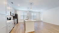 Located at 1801 Diamond Pkwy in North Kansas City, MO, this two-bedroom, one-bathroom residence offers a thoughtfully designed single-floor layout with a clean, modern aesthetic. The open-concept kitchen and living area serves as the heart of the home, anchored by a large center island with a quartz countertop, undermount sink, and stylish globe pendant lighting. The kitchen features shaker-style cabinetry, a white subway tile backsplash, stainless steel appliances, and generous counter space, flowing seamlessly into the living area bathed in natural light from multiple windows with white blinds. Light wood-style flooring extends throughout the entire residence, creating a warm and cohesive feel. The primary bedroom offers a comfortable footprint with abundant natural light and direct access to the full bathroom, which is appointed with a quartz vanity countertop, undermount sink, and a large mirror. A walk-in closet with wire shelving provides practical storage. The second bedroom is bright and well-proportioned, featuring its own window and easy access to additional closet space. With three closets total, storage is plentiful. The consistent use of white walls, recessed lighting, and modern hardware throughout gives the space a fresh, contemporary character.