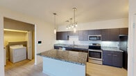 Located at 455 South Recker Road in Gilbert, AZ, this well-appointed one-bedroom, one-bathroom residence offers a thoughtfully designed single-floor layout. The kitchen serves as a standout centerpiece, featuring a large granite-topped island, dark espresso cabinetry, stainless steel appliances including a range, microwave, and refrigerator, and stylish pendant lighting overhead. Light wood-look flooring flows throughout the main living and kitchen areas, enhancing the clean, contemporary aesthetic.

The bedroom is a comfortably sized retreat finished with plush carpeting, a ceiling fan, and multiple windows that allow natural light to fill the room. An adjoining walk-in closet provides generous storage with double hanging rods and built-in shelving on multiple walls.

The bathroom is finished with the same light tile flooring as the kitchen and features a tub-shower combination with sliding glass doors, a dark-cabinetry vanity with white countertop, and brushed nickel hardware and grab bars throughout. A hallway connects the main living areas to the private spaces, completing a practical and efficient floor plan well-suited for comfortable everyday living in the Gilbert, AZ area.