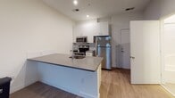 This single-floor residence at 1810 Highpoint Ave in Richmond, Virginia offers a clean, modern aesthetic with thoughtfully designed living spaces. The open-concept kitchen serves as a centerpiece of the unit, featuring a large peninsula with a sleek stone countertop and an integrated sink, ideal for both meal preparation and casual dining. White shaker-style cabinetry extends to the ceiling, maximizing storage, while a full suite of stainless steel appliances — including a refrigerator, electric range, and microwave — lends a polished, contemporary feel. Light wood-tone flooring runs throughout the main living and kitchen areas, adding warmth to the bright, neutral-toned interior. The bedroom is a comfortable, quiet retreat finished with soft carpeting and a large sliding window that allows natural light to fill the room while offering views of the surrounding community. The bathroom is clean and functional, finished with light tile flooring and featuring a tub-shower combination with chrome fixtures, a toilet, and a louvered storage closet. Recessed lighting throughout the unit provides consistent, even illumination, while the crisp white walls create a fresh and versatile backdrop. This well-appointed space combines modern finishes with practical design for comfortable everyday living.