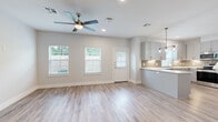 This well-designed two-story home offers 2 bedrooms and 4 bathrooms, thoughtfully laid out across two floors. The main level centers on an open-concept living and kitchen area, where light-toned luxury vinyl plank flooring, neutral gray walls, and a ceiling fan create a bright, airy atmosphere. Multiple windows flood the space with natural light, while a front entry door provides convenient access. The kitchen is a standout feature, showcasing gray shaker-style cabinetry, a decorative tile backsplash, quartz countertops, stainless steel appliances, and a peninsula with stylish pendant lighting overhead. The main level also includes a dedicated laundry area equipped with a full-size washer and dryer. An attached two-car garage with an automatic opener provides ample storage and parking. Upstairs, the primary bedroom is generously sized and carpeted for comfort, accompanied by a walk-in closet with built-in shelving and hanging rods. The bathrooms are finished with gray vanity cabinetry, quartz countertops, brushed gold fixtures, large mirrors, and tile-surround tub and shower combinations. Clean lines, neutral tones, and modern finishes are consistent throughout, giving the entire home a cohesive, contemporary feel.