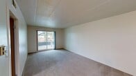 Located at 2020 W Alexis Rd in Toledo, Ohio, this single-floor unit offers a practical and straightforward layout across two bedrooms, one bathroom, and a kitchen. The living area features neutral carpet flooring and a textured ceiling, with a sliding glass door that introduces natural light and provides access to an outdoor balcony area with views of surrounding trees. The open wall space offers flexibility for a variety of furniture arrangements.

The kitchen is equipped with warm-toned wood cabinetry, a white electric range, a refrigerator, and a built-in sink with adjacent counter space. Light hardwood-style flooring runs throughout the kitchen, and a ceiling fan with overhead lighting adds both comfort and function to the space. A skylight panel brightens the kitchen naturally.

The generously sized primary bedroom features carpet flooring, a large window overlooking greenery, and a sliding-door closet with built-in shelving. The second bedroom is also carpeted and includes a dedicated closet with rod and shelf storage, with direct access to the kitchen area. The bathroom includes a full tub-shower combination, tile flooring with a classic mosaic pattern, a vanity, and a skylight panel overhead for added brightness.