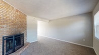 This two-story home offers a practical and comfortable layout spread across two levels, connected by an interior staircase. The main living area is a generously sized, carpet-floored space highlighted by a full-height brick fireplace surround — a standout architectural feature that adds warmth and character to the room. Neutral-toned walls and multiple windows allow natural light to filter in, creating a bright and open atmosphere. A front entry door is flanked by two windows that offer views of the surrounding greenery.

The kitchen is functional and well-appointed, featuring gray cabinetry, wood-look flooring, a full suite of white appliances including a refrigerator, electric range, microwave, and dishwasher, along with a ceiling fan nearby. A sliding glass door provides additional light and access to the exterior.

The bedrooms are carpeted and finished with neutral walls, each featuring windows that bring in natural light. The bathrooms are clean and practical, with one featuring a tub-shower combination, wood-look tile flooring, and gray vanity cabinetry with a white countertop. A second bathroom provides a vanity with a marble-look countertop and a mirrored medicine cabinet. The home also includes a dedicated in-unit laundry area with a full-size washer and dryer and overhead shelving.