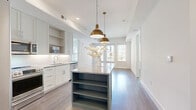 Located at 7395 E Legacy Blvd in Scottsdale, Arizona, this thoughtfully designed two-bedroom, two-bathroom residence offers a clean, contemporary aesthetic across a single level. The open-concept kitchen serves as the heart of the home, showcasing a striking colored island with a granite countertop, open shelving below, and eye-catching brass pendant lights overhead. Light gray shaker-style cabinetry lines the walls, complemented by a white subway tile backsplash, stainless steel appliances, and granite countertops throughout. Wood-look flooring flows seamlessly from the kitchen into the living area and hallway, lending warmth and cohesion to the space. Both bedrooms are bright and airy, benefiting from large windows that invite natural light and provide views of the surrounding Scottsdale community. The primary bedroom includes a dedicated walk-in closet with built-in shelving and hanging rods finished with gold-toned hardware. Both bathrooms mirror each other in design, each featuring a dark green vanity with granite countertops, sleek vertical wall sconces, subway tile surrounds in the tub/shower combinations, and distinctive patterned tile flooring that adds a sophisticated decorative touch. Clean white walls and recessed lighting throughout maintain a bright, modern ambiance well-suited to the Scottsdale lifestyle.