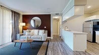 Located at 7871 Mission Grove Pkwy S in Riverside, CA, this thoughtfully designed one-bedroom, one-bathroom residence offers a efficient and stylish single-floor layout. The open-concept living, dining, and kitchen area forms the heart of the home, with wood-look flooring, crown molding, and recessed lighting throughout. The living room features a bold deep-red accent wall with a circular mirror, creating a striking focal point, while a sliding glass door floods the space with natural light and opens to a private patio with views of the surrounding community. The kitchen is outfitted with stainless steel appliances, white shaker cabinetry, subway tile backsplash, and a peninsula counter, flowing seamlessly into a dedicated dining area. The bedroom offers a serene retreat with a rich teal accent wall, ceiling fan, and windows dressed with navy curtains that filter in natural light. The bathroom features a clean, white vanity with a undermount sink and crisp cabinetry, complemented by an adjacent in-unit washer and dryer. A hallway with a closet provides additional storage. The overall aesthetic blends modern and mid-century influences for a cohesive, contemporary feel.