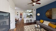 This single-floor residence offers a thoughtfully designed open-concept layout that seamlessly connects the living, dining, and kitchen areas. Rich dark hardwood-style flooring flows throughout the main living spaces, anchoring the contemporary aesthetic. The living room is highlighted by a bold navy blue accent wall, a ceiling fan, and a window that brings in natural light, creating a vibrant yet comfortable atmosphere.

The kitchen is well-equipped with stainless steel appliances including a refrigerator, gas range, microwave, and dishwasher, complemented by white shaker-style cabinetry, grey countertops, and a peninsula with bar seating — ideal for casual dining or entertaining. Adjacent to the kitchen, the dining area features a wood-paneled accent wall and direct sightlines to the hallway leading to the bedroom.

The bedroom is a standout space, featuring an exposed red brick accent wall that adds warmth and texture, along with a ceiling fan and a window for natural light. The bathroom includes a full tub-shower combination with white tile surround and a curved curtain rod. A dedicated in-unit laundry area with full-size washer and dryer adds everyday convenience. Together, these spaces deliver a cohesive, modern living experience with distinctive design details throughout.