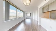 Located at 1 City Place in White Plains, NY, this well-appointed 2-bedroom, 2-bathroom residence offers a thoughtfully designed single-floor layout. Dark hardwood flooring runs through the entryway hallways, transitioning seamlessly into the expansive living room, which is bathed in natural light from large floor-to-ceiling windows offering sweeping panoramic views of the White Plains skyline and surrounding landscape. Crown molding and elegant wall sconces add refined touches throughout. The galley-style kitchen is outfitted with stainless steel appliances, warm wood cabinetry, light stone countertops, and tile flooring, complemented by a pantry for additional storage. Both bedrooms feature hardwood floors and generous windows that frame impressive elevated views — the primary bedroom enjoys corner window placement capturing both city and open sky vistas. Both bathrooms are finished with warm beige marble-style tile, pedestal sinks, and full soaking tubs with shower combinations. The residence is further enhanced by five closets, a dedicated laundry area, and two hallways that provide an efficient flow between spaces. This residence offers a bright, clean, and functional living environment in the heart of White Plains.