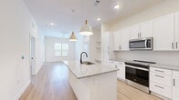 Located at 11385 Exchange Street in Jacksonville, FL, this well-appointed one-bedroom, one-bathroom residence offers a thoughtfully designed open-concept floor plan. Light-toned luxury vinyl plank flooring flows throughout the main living areas, complemented by a crisp, neutral color palette and recessed lighting that enhances the bright, airy atmosphere.

The kitchen serves as the heart of the home, featuring a central island with a granite countertop, an undermount sink with a matte black faucet, and pendant lighting overhead. White shaker-style cabinetry with black hardware lines the walls, accompanied by stainless steel appliances including a range, microwave, and refrigerator, as well as open shelving for additional storage.

The kitchen opens seamlessly into the living room, which benefits from natural light through a large window and is equipped with a ceiling fan. The bedroom offers plush carpeted flooring, a ceiling fan, and a generously sized window with outdoor views. A spacious walk-in closet with wire shelving provides ample storage.

The bathroom continues the home's cohesive design with granite countertops, white cabinetry, matte black fixtures, a framed mirror, and a full tub-shower combination with white tile surround, all set on wood-look flooring.