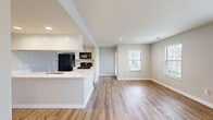 Located at 700 Vista Dr in Gahanna, Ohio, this single-floor, 2-bedroom, 1-bathroom home offers a clean, modern aesthetic with thoughtful finishes throughout. The open-concept kitchen and living area serves as the heart of the home, featuring striking quartz countertops with elegant veining, white shaker-style cabinetry, a large undermount sink with a brushed nickel faucet, and black appliances including a gas range, microwave, refrigerator, and dishwasher. Light wood-style flooring runs throughout the main living areas, complementing the neutral gray wall tones and crisp white trim. The living room is bright and airy, lined with multiple windows fitted with white blinds that invite generous natural light and outdoor views. The spacious primary bedroom offers plush carpeting, dual sliding closet doors for ample storage, and windows providing outdoor views. The second bedroom also features soft carpeting and natural light. The bathroom is conveniently accessible from the hallway and includes a vanity with white cabinetry. A dedicated hallway with closet storage and wood-style flooring connects the main living spaces to the bedrooms, adding to the home's functional and cohesive layout.