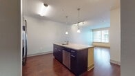 This contemporary 700 square foot apartment offers a thoughtful blend of comfort and functionality. The space is efficiently designed with one bedroom, one bathroom, and an open-concept living area. The primary bedroom, measuring 130 square feet, provides ample space and features plush carpeting and a large window for natural light.

The bathroom is elegantly appointed with a dual vanity, large mirror, and a combination tub and shower, finished with high-quality tile work. The kitchen is a highlight, boasting sleek dark cabinetry, stainless steel appliances, and granite countertops. It opens to the living area, creating a seamless flow for entertaining.

Rich hardwood floors run throughout the main living spaces, adding warmth and sophistication. The apartment also includes a dedicated office area and a closet for additional storage. Large windows in the living room and bedroom offer plenty of natural light and views of the surrounding area.

The overall design emphasizes a neutral color palette, creating a calm and versatile living environment. With its modern amenities and thoughtful layout, this apartment provides a comfortable and stylish urban living experience.