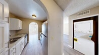Located at 1601 E Katie Ave in Las Vegas, NV, this 1-bedroom, 2-bathroom unit offers a thoughtfully designed single-floor layout. The living room serves as the heart of the home, featuring light wood-style flooring, a ceiling fan, a tiled fireplace, and an arched window that invites natural light into the space. A decorative arched passageway connects the living room to the kitchen, adding a distinctive architectural touch throughout. The kitchen is well-appointed with white cabinetry, granite-style countertops, stainless steel appliances including a refrigerator, gas range, and dishwasher, along with a double sink. A stacked washer and dryer unit is conveniently accessible from the hallway. The bedroom features soft carpeting, a ceiling fan, a closet, and direct access to one of the two bathrooms. The bathrooms are clean and functional, with one featuring a full soaking tub, a single-sink vanity with white cabinetry, and wood-style flooring. Neutral tones and textured ceilings are consistent throughout, giving the unit a cohesive and comfortable feel. The efficient layout makes excellent use of the available space, offering practical living in a centrally located Las Vegas address.
