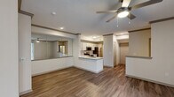 Located at 3700 Preston Rd in Plano, TX, this 2-bedroom, 2-bathroom residence offers a well-designed single-level layout that balances comfort and functionality. The open-concept living and kitchen area is anchored by rich wood-style flooring and a ceiling fan, creating an airy, welcoming atmosphere. A large sliding glass door floods the living room with natural light and opens to a private balcony with greenery views, while a mirrored wall accent enhances the sense of space.

The kitchen is a standout feature, showcasing quartz countertops with elegant veining, white shaker cabinetry, a tile backsplash, stainless steel appliances, and a peninsula with a built-in sink — ideal for both cooking and casual entertaining. Crown molding details add a refined touch throughout the main living areas.

Both bedrooms are carpeted and finished with neutral tones, offering a calm and restful environment. Each room is served by a dedicated closet. The bathrooms are outfitted with white vanities, quartz countertops, framed mirrors, and a tub-shower combination with tile surround. Wood-style flooring continues into the bathrooms for a cohesive finish. Two dedicated closets provide ample storage throughout the home.
