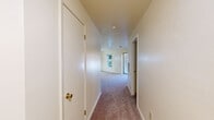 This single-floor, 2-bedroom, 2-bathroom residence in Chestertown, MD offers a practical and comfortable layout designed for everyday living. The interior is finished with soft wall-to-wall carpeting throughout the main living areas, hallway, and bedrooms, lending a warm, cohesive feel to the home. The living area is bright and open, highlighted by a sliding glass door that invites natural light and provides direct access to the outdoors with views of surrounding greenery. The kitchen features warm wood-toned cabinetry, white appliances including a range and refrigerator, and ample counter space for meal preparation. A central hallway connects the living spaces to the two bedrooms and both bathrooms, providing a logical and organized flow. The primary bedroom is generously sized and benefits from natural light through a large window, with views of the outdoors. It is complemented by a dedicated walk-in closet complete with wire shelving for organized storage. The second bedroom also features a large window with outdoor views and includes a built-in double closet. Both bathrooms are equipped with full tub-shower combinations, vanities, and tile flooring. The space presents a clean, functional design well-suited for comfortable residential living.