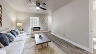 Located at 1550 Blalock Rd in Houston, TX, this two-story home offers 2 bedrooms and 3 bathrooms thoughtfully distributed across two floors. The main level features an open-concept living and dining area with warm hardwood-style flooring, neutral gray walls, and ceiling fans throughout. The living room is bright and welcoming, highlighted by natural light from large windows, and flows seamlessly into the dining area. The kitchen is well-appointed with white shaker-style cabinetry, light countertops, a gray subway tile backsplash, and black appliances, including a refrigerator and dishwasher. The bathrooms feature white vanities with under-cabinet storage, mirrored medicine cabinets, and clean, modern finishes. One bathroom includes a soaking tub with white tiled surround. The primary bedroom, located on the upper floor, is a comfortable retreat with a ceiling fan, natural light from a window, and access to a closet. The second bedroom also features a ceiling fan, window, and its own closet for ample storage. Hardwood-style flooring runs consistently throughout both levels, tying the home together with a cohesive, contemporary aesthetic. Two staircases connect the floors, and a hallway provides convenient circulation between rooms.