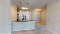 This single-story, 2-bedroom, 2-bathroom residence offers a thoughtfully designed layout with modern finishes throughout. The open-concept living and kitchen area forms the heart of the home, where a peninsula island with dark granite countertops and pendant lighting serves as a natural focal point. The kitchen is equipped with stainless steel appliances, including a refrigerator, range, and microwave, complemented by crisp white cabinetry and a classic white subway tile backsplash. Rich wood-tone flooring runs through the kitchen and hallways, while plush carpeting extends through the living area and bedrooms, adding warmth and comfort.

The living area is generously sized with a ceiling fan, track lighting, and a neutral color palette that creates a bright, inviting atmosphere. Both bedrooms are well-proportioned, featuring large windows with blinds that allow ample natural light and views to the outdoors. The primary bedroom benefits from multiple windows and ceiling fan, while one bedroom includes a walk-in closet with built-in shelving.

Both bathrooms mirror the home's refined aesthetic, featuring white vanity cabinetry, dark granite countertops, and wood-tone flooring. Each bathroom includes a tub/shower combination. The overall design balances contemporary finishes with functional, comfortable living spaces.