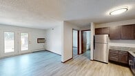 Located at 614 W Bridge St in Owatonna, Minnesota, this one-bedroom, one-bathroom unit offers a practical and comfortable single-floor layout. The kitchen is a standout feature, outfitted with rich dark-brown cabinetry, granite-style countertops, and a full suite of stainless steel appliances including a refrigerator, range, and dishwasher. Light wood-look vinyl flooring runs throughout the kitchen and living areas, lending a clean, modern aesthetic. The living room is bright and open, with a large window that allows natural light to fill the space, a wall-mounted air conditioning unit, and a baseboard heating system for year-round comfort. A door from the living area provides additional access and light. The bedroom is comfortably sized, featuring plush carpeting, a ceiling fan with light fixture, a window with exterior views, and a double-door closet offering generous storage. Warm wood-toned door trim and baseboards add a cohesive touch throughout the unit. The bathroom is well-appointed with a granite-topped vanity, dark cabinetry, a large mirror, modern light fixtures, and a shower with a decorative curtain, all set on easy-care vinyl flooring. Textured ceilings are present throughout, adding a classic residential character to the space.