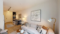 Located at 424 East 36th Street in Charlotte, NC, this thoughtfully designed one-bedroom, two-bathroom residence offers a clean, contemporary aesthetic across a single floor. The open-concept kitchen and living area serves as the heart of the home, featuring stainless steel appliances, granite countertops, dark wood cabinetry, and white upper shelving. Track lighting illuminates the galley-style kitchen, which flows seamlessly into the dining area — anchored by a versatile island with bar seating — and into a bright living room. Floor-to-ceiling sliding glass doors in the living room flood the space with natural light and open to a private balcony overlooking the surrounding neighborhood. The bedroom is a comfortable retreat with a ceiling fan, natural window light, and a stylish barn door that leads to a built-in closet area with organized shelving. The two bathrooms are finished with granite-topped vanities, dark wood cabinetry, and warm wood-look flooring. A hallway with additional storage connects the rooms efficiently. Throughout, light wood flooring, neutral walls, and modern fixtures create a cohesive, contemporary atmosphere well-suited to urban living in Charlotte's vibrant 28205 corridor.
