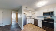 Located at 11712 Tazwell Ct in Louisville, KY, this single-floor residence offers a thoughtfully updated interior with a cohesive blend of modern finishes throughout. The open layout connects the main living area to the kitchen, which serves as a functional centerpiece of the space. The kitchen is well-appointed with white shaker-style cabinetry, granite countertops, a classic subway tile backsplash, and a full suite of stainless steel appliances including a refrigerator, dishwasher, and range. Wood-look flooring runs throughout the main living areas, adding warmth and visual continuity.

The living area is bright and open, highlighted by French doors that lead to a private balcony, allowing natural light to fill the space and offering outdoor views. Bedrooms are carpeted for comfort and include windows with blinds that provide natural light while maintaining privacy. Neutral wall tones throughout create a versatile backdrop.

The bathrooms are finished with white vanity cabinetry, granite-topped counters, and large-format marble-look tile surrounding both the tub/shower combo and a separate walk-in shower, lending a clean, polished aesthetic to these functional spaces.