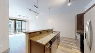 This contemporary 620 square foot apartment in Baltimore offers a perfect blend of style and functionality. The open-concept design maximizes space, seamlessly connecting the living area with the gourmet kitchen. The kitchen boasts dark wood cabinetry, stainless steel appliances, and granite countertops, complete with a built-in wine rack for entertaining.

The single bedroom, measuring 130 square feet, features large windows that flood the space with natural light. A ceiling fan adds both style and comfort. The two bathrooms are finished with modern fixtures, including a spacious tub with elegant tile work, and granite-topped vanities.

Throughout the apartment, grey-toned wood-look flooring creates a cohesive and sophisticated aesthetic. Large windows in the living area and bedroom not only brighten the space but also offer views of the surrounding cityscape. The apartment's layout includes a closet for additional storage.

High ceilings and recessed lighting contribute to the airy feel of the space. The property's location at 1200 S. Conkling Street places residents in the heart of Baltimore, offering urban convenience with a touch of luxury. This single-floor residence combines modern design with practical living, ideal for those seeking a contemporary urban lifestyle.