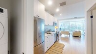 Located on Wilshire Boulevard in the heart of Los Angeles, this thoughtfully designed studio offers a modern, efficient layout across a single floor. The open-plan kitchen and living area is bathed in natural light from expansive floor-to-ceiling windows, which frame striking views of the surrounding cityscape. Light hardwood flooring runs throughout, lending warmth and continuity to the space.

The kitchen is outfitted with sleek white cabinetry extending to the ceiling, a textured tile backsplash, light quartz countertops, and a full suite of stainless steel appliances including a refrigerator, range, microwave, and dishwasher. The living area accommodates comfortable seating and a dining setup, all oriented to take full advantage of the panoramic urban views.

The bathroom is clean and contemporary, featuring a white vanity with quartz countertop, tiled tub-shower combination, and neutral tile flooring. A generously sized walk-in closet provides ample storage with built-in shelving units and multiple hanging rods along the walls. The overall ambiance of the space is bright, modern, and urban, making it a well-appointed residence in one of Los Angeles's most prominent corridors.
