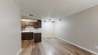 This single-floor unit offers a clean, functional layout with wood-look flooring carried consistently throughout the space, creating a cohesive and low-maintenance aesthetic. The open-concept kitchen is a standout feature, equipped with rich dark cabinetry, a stylish tile backsplash, white countertops, a double stainless steel sink, and a stainless steel refrigerator. A peninsula-style counter separates the kitchen from the adjoining living and dining area, which is fitted with a ceiling fan and light fixture. The living area is generously proportioned, with neutral warm-toned walls and a textured ceiling that adds subtle visual depth. A front-facing window with horizontal blinds allows natural light to fill the space, while a dedicated entryway door provides direct access. Additional rooms include well-sized bedrooms, each with windows fitted with blinds to control light and privacy. The bathroom features a full-size soaking tub and shower combination, surrounded by classic large-format tile with a decorative mosaic accent border, complemented by wood-look flooring. Throughout, clean white baseboards and neutral walls provide a versatile backdrop suited to a variety of interior styles.