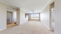 This single-floor, 2-bedroom, 2-bathroom residence features a thoughtfully designed layout that balances comfort and functionality. The spacious living area is finished with plush neutral carpeting, crown molding, and a ceiling fan, while a large window invites generous natural light and outdoor views, creating an open and airy atmosphere.

The kitchen is well-equipped with rich dark wood cabinetry, warm countertops, black appliances including a refrigerator, stove, and dishwasher, and durable hardwood-style flooring. A breakfast bar peninsula separates the kitchen from the living area, and a windowed door provides additional natural light and exterior access.

The primary bedroom is a generously sized retreat featuring a ceiling fan, plush carpeting, crown molding, and a window with outdoor views. A dedicated closet adds practical storage. The second bedroom is similarly comfortable, with carpet flooring and a window that brings in natural light.

Both bathrooms are finished consistently, each featuring a tub-shower combination with tiled surround, dark wood vanity cabinetry, light countertops, and hardwood-style flooring. Two hallways and two closets throughout the residence provide ample circulation and storage. The neutral color palette and cohesive finishes lend a clean, move-in ready feel to the entire space.