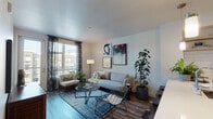 Located at 579–585 S First St in the heart of San Jose, CA, this single-floor residence offers a thoughtfully designed open-concept layout finished with modern details throughout. Wood-style flooring flows continuously across the living, kitchen, and bedroom areas, creating a cohesive and polished aesthetic.

The living area is bright and welcoming, anchored by large windows and a glass balcony door that invite abundant natural light and provide views of the surrounding urban streetscape. Sheer patterned drapes add a stylish layer to the space.

The kitchen is well-appointed with light wood cabinetry, white subway tile backsplash, quartz countertops, and a full suite of stainless steel appliances. A peninsula with bar seating and pendant lighting makes the space ideal for casual dining and entertaining.

The bedroom features a large window, wood-style flooring, and a striking scenic mural wallcovering as a focal point. A walk-in closet provides ample storage. The bathroom complements the overall design with cool blue-gray walls, wood-finish vanity cabinetry, quartz countertops, and a full tub-shower combination, maintaining a clean, contemporary feel throughout.
