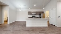 Located at 3423 Miller Rd in Arnold, Missouri, this single-floor unit features a thoughtfully designed open-concept layout that seamlessly connects the kitchen and living area. The kitchen is a standout, showcasing dark espresso cabinetry, granite countertops, a subway tile backsplash, and a full suite of stainless steel appliances including a range, microwave, and refrigerator. A central island with a built-in sink and additional granite surface provides both prep space and a natural gathering point. Pendant lighting above the island complements the recessed lighting throughout, enhancing the bright, airy atmosphere created by the soaring vaulted ceilings.

The living area extends naturally from the kitchen, featuring wood-look flooring and sliding glass doors that allow natural light to fill the space. Bedrooms are carpeted for comfort, with vaulted or standard ceilings depending on the room, and feature ceiling fans and windows with blinds. Two bathrooms serve the unit: one with a glass-enclosed shower and granite vanity, and another with a full tub-shower combo and matching granite vanity. Dark cabinetry in both bathrooms ties cohesively to the kitchen's design. The overall aesthetic is clean, modern, and move-in ready.