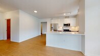 Located at 200 Townsfolk Alley in Penfield, NY, this well-designed 2-bedroom, 2-bathroom single-floor residence offers a clean, modern aesthetic throughout. The entry hallway welcomes you with crisp white walls, light bamboo-style hardwood flooring, and a built-in utility panel, setting the tone for the home's contemporary style.

The open-concept kitchen and living area is bright and functional. The kitchen features two-tone cabinetry — warm wood lower cabinets paired with white upper cabinets — complemented by light quartz countertops, stainless steel appliances including a refrigerator, range, and microwave, and a peninsula with a sink that overlooks the living space. A large window allows natural light and outdoor greenery views into the kitchen.

The living room is spacious and airy, with the same hardwood flooring and recessed lighting providing a clean, uncluttered environment.

The generously sized primary bedroom is carpeted for comfort and features dual windows with outdoor views, filling the room with natural light. It includes a walk-in closet with wire shelving. The second bedroom also features hardwood flooring and dual windows overlooking the surroundings.

Both bathrooms are finished with wood-tone vanities, white countertops, and matching hardwood floors. A dedicated utility room completes the practical layout of this thoughtfully designed residence.