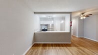 Located at 4702 Mangum Rd in Houston, TX, this single-story, one-bedroom, one-bathroom unit offers a practical and cohesive layout across its efficiently organized floor plan. Warm-toned wood-look flooring runs consistently throughout the space, creating visual continuity between rooms.

The combined kitchen and living area forms the heart of the unit. The kitchen features white cabinetry with brushed nickel hardware, light stone-look countertops, a stainless steel double-basin sink with a modern pull-down faucet, and a stainless steel refrigerator. Track lighting illuminates the kitchen, which opens to the living area via a half-wall counter. The living room is bright and airy, with a ceiling fan overhead, neutral gray walls, and a window that lets in natural light.

The bedroom is a comfortable, well-proportioned room with the same wood-look flooring, a ceiling fan with light fixture, a window with outdoor views of greenery, and access to a dedicated closet. The textured ceiling adds a classic touch.

The bathroom is finished with large-format beige ceramic wall tiles in the tub/shower surround, a soaking tub with a curtain rod, a window for natural light and ventilation, wood-look flooring, and a white vanity with sink. The overall ambiance is clean, functional, and move-in ready.