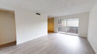 This well-maintained single-floor unit offers a bright, open layout finished with light hardwood-style flooring that runs seamlessly throughout the space. The spacious living area is a standout feature, bathed in natural light from large sliding glass doors that open onto a private balcony with views of surrounding greenery — an inviting connection between indoor and outdoor living. The textured ceiling adds a classic architectural detail that complements the clean white walls.

The galley-style kitchen is efficiently designed, featuring white cabinetry, dark granite countertops, a tile backsplash, and stainless steel appliances including a range and microwave. A full-size pantry door provides ample storage within the kitchen corridor.

The bedrooms are generously proportioned, each with light-toned flooring, neutral walls, and windows that allow for natural light and ventilation. The rooms offer a clean, versatile canvas well-suited for a variety of layouts.

The bathroom is tastefully updated, showcasing floor-to-ceiling large-format tile in rich earth tones surrounding a full soaking tub and shower combination, paired with chrome fixtures for a polished finish.

Overall, this unit presents a cohesive, move-in ready aesthetic with a neutral palette, practical layout, and comfortable features throughout.