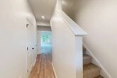 Located at 1061 Dryden Rd in Ithaca, NY, this two-story home offers 2 bedrooms and 3 bathrooms across two well-proportioned floors. The main level features an open-concept kitchen and living area filled with natural light from large windows and sliding glass doors that frame serene, lush greenery. The kitchen is outfitted with white cabinetry, stainless steel appliances, a quartz peninsula countertop with a black matte sink fixture, and pendant lighting — a clean, modern aesthetic throughout. Hardwood-style flooring runs across the main level, complementing the bright, neutral color palette. An attached garage with an automatic opener provides convenient enclosed parking. Upstairs, the upper floor hosts both bedrooms, including a spacious primary bedroom with plush carpeting, a ceiling fan, and windows overlooking wooded surroundings. The primary suite connects to a walk-in closet with built-in wire shelving and a natural light source. The bathrooms are finished with modern fixtures, including a glass-enclosed shower with matte black hardware. Additional spaces include multiple closets, a dedicated laundry area, a utility room, and well-placed hallways connecting each floor via carpeted staircases with crisp white railings.
