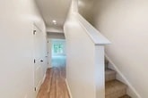 Located at 1061 Dryden Rd in Ithaca, NY, this two-story home offers 2 bedrooms and 3 bathrooms across two well-proportioned floors. The main level features an open-concept kitchen and living area filled with natural light from large windows and sliding glass doors that frame serene, lush greenery. The kitchen is outfitted with white cabinetry, stainless steel appliances, a quartz peninsula countertop with a black matte sink fixture, and pendant lighting — a clean, modern aesthetic throughout. Hardwood-style flooring runs across the main level, complementing the bright, neutral color palette. An attached garage with an automatic opener provides convenient enclosed parking. Upstairs, the upper floor hosts both bedrooms, including a spacious primary bedroom with plush carpeting, a ceiling fan, and windows overlooking wooded surroundings. The primary suite connects to a walk-in closet with built-in wire shelving and a natural light source. The bathrooms are finished with modern fixtures, including a glass-enclosed shower with matte black hardware. Additional spaces include multiple closets, a dedicated laundry area, a utility room, and well-placed hallways connecting each floor via carpeted staircases with crisp white railings.