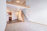 Located at 1118 N Pleasant View Rd in Madison, Wisconsin, this two-story home offers a practical and comfortable layout across two floors. The main level provides an welcoming entry through a hallway that connects to the kitchen and primary living areas. The kitchen is well-appointed with rich, warm-toned cabinetry, light stone-patterned countertops, a breakfast bar peninsula, hardwood-style flooring, and a full suite of white appliances including a refrigerator, range, and over-the-range microwave. A staircase with a wooden banister connects the two floors, serving as a functional architectural centerpiece. The upper level features a spacious loft with vaulted ceilings that lend an open, airy feel, alongside the bedroom, which offers plush carpeting, a large window with outdoor views, and a sloped ceiling. Two closets provide ample storage throughout the home. Both bathrooms are clean and functional — one features a glass-enclosed shower stall with wood-toned cabinetry and a large mirror, while the second includes a full tub-shower combo with matching fixtures and countertops. Warm wood trim accents are consistent throughout the space, tying together the neutral color palette and creating a cohesive, inviting atmosphere.