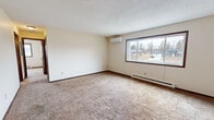 Located at 332 Cypress Dr in Saint Joseph, MN, this single-floor unit offers four bedrooms, one bathroom, and a practical layout designed for comfortable everyday living. The living area features neutral carpet, a textured ceiling, a wall-mounted mini-split air conditioning unit, and a large picture window that fills the room with natural light and provides views of the surrounding neighborhood. Baseboard heating runs throughout the unit, ensuring warmth during Minnesota winters. The kitchen is equipped with wood cabinetry, white appliances including a refrigerator and electric range, a double sink, and tile flooring that extends into the entryway. A ceiling fan is visible in the transitional area connecting the living space to the kitchen. The four bedrooms are carpeted with neutral tones, each featuring windows for natural light and baseboard heating. The primary bedroom is generously sized and includes a sliding closet with built-in shelving. The full bathroom includes a single-sink vanity with storage, a toilet, a tub-shower combination with a white surround, and tile flooring. Dark wood trim and doors appear consistently throughout the unit, lending a cohesive, classic feel to the overall interior.