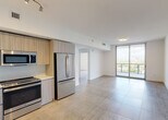 Located in Miami's vibrant Coconut Grove neighborhood, this contemporary residence offers a sleek, modern design throughout. The open-concept living and dining area is anchored by large-format tile flooring and floor-to-ceiling sliding glass doors that lead to a private balcony, flooding the space with natural light and offering impressive elevated views of the Miami skyline and surrounding greenery.

The kitchen is outfitted with light wood-toned cabinetry extending to the ceiling, white quartz countertops, and a full suite of stainless steel appliances including a French-door refrigerator, gas range, built-in microwave, and dishwasher. A dedicated wet bar area with an under-mounted sink adds extra functionality.

The bedroom is generously proportioned with neutral tile flooring, crisp white walls, and a built-in closet with shelving. An additional room provides flexible use as a second bedroom or office. The bathroom features a soaking tub with overhead shower, white tile surround, a floating wood-finish vanity, and a window that brings in natural light while maintaining privacy. Throughout, the clean white palette and consistent tile flooring create a cohesive, contemporary aesthetic.