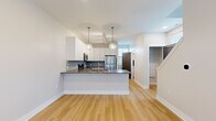 This two-story home in Green, Ohio offers a well-organized layout across two floors, combining modern finishes with functional living spaces. The main floor features a bright, open-concept kitchen equipped with white shaker-style cabinetry, a blue subway tile backsplash, dark granite countertops, a center island with pendant lighting, and stainless steel appliances including a refrigerator, range, and over-the-range microwave. Light hardwood flooring extends throughout the main level, complementing the clean, neutral color palette. The living room provides an open, airy feel with crisp white walls and easy access to the rest of the main floor. A hallway and convenient bathroom round out the first floor. Carpeted stairs with white-painted railings lead to the upper level, where two bedrooms are situated. The spacious primary bedroom features plush carpet, large windows offering neighborhood views, and access to a well-appointed walk-in closet with wire shelving systems for organized storage. The second bedroom is similarly carpeted and well-lit with multiple windows. Three bathrooms are distributed across both floors, including one with granite countertops, white cabinetry, and light hardwood floors. Throughout the home, neutral tones and contemporary finishes create a clean, move-in-ready atmosphere.